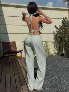 Back view of mint green striped halter top and wide leg pants set on a sunny terrace