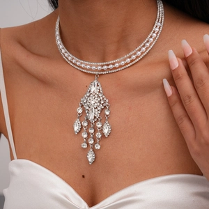 Close-up of a three-layer rhinestone and pearl choker with a tassel pendant on a model