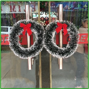 Detail of Christmas wreaths with red bows hanging on a glass door handle