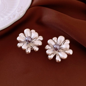 Close-up of silver flower earrings with grey pearl center on elegant silk fabric background