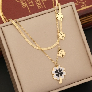 Double-layered gold clover necklace with snake chain displayed in a beige jewelry box