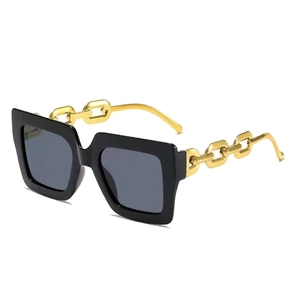 Oversized square sunglasses in black with gold chain temples shown at a 45-degree angle