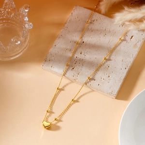 Detailed macro of 18K gold plated heart pendant necklace on minimalist beaded chain link