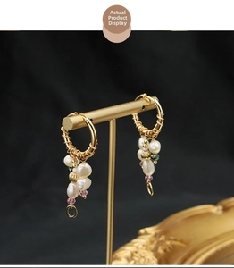 Detailed shot of baroque gold hoop earrings with irregular pearls on a T-stand display