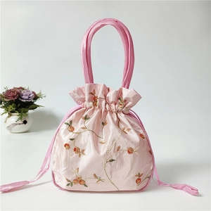Close-up of pink satin drawstring bag with floral embroidery and tassel detail