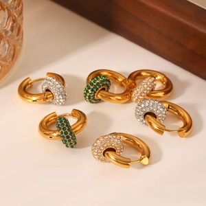Dettaglio di orecchini a cerchio in acciaio 18K con ciondoli in zircone verde e bianco