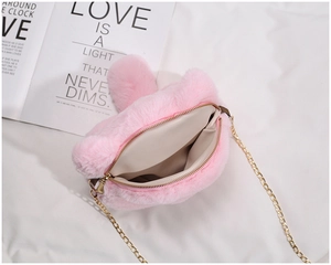 Close-up of pink plush bag with golden metal chain strap and top zipper detail
