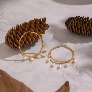 Detailed shot of gold hoop earrings with white freshwater pearls on marble background