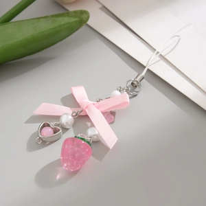 Detail showing a pink strawberry charm with silk ribbon, white pearls, and heart element