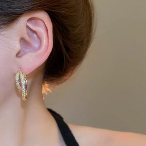 Close-up of 18k gold plated U-shaped earrings with pave-set cubic zirconia on a model