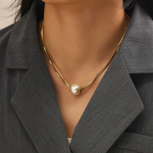 Elegant double-layered gold snake chain necklace with large pearl pendant on a model