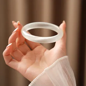 Translucent cat eye stone bracelet with warm white matte finish held against dark fabric