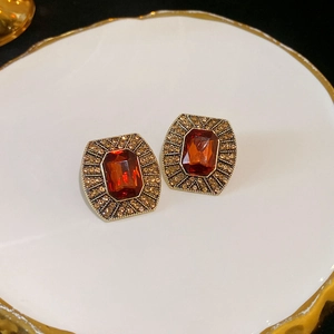 Détail de boucles d'oreilles vintage dorées avec pierre ambre et pavé sur plateau agate