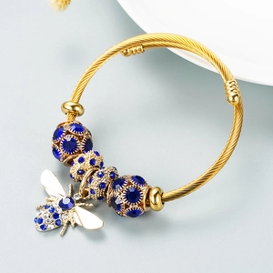 Adjustable gold twisted bangle featuring dark blue rhinestones and detailed bee charm