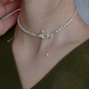 Detail of s925 silver pearl necklace with butterfly pendant on model neck
