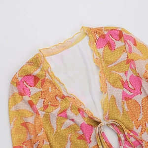 Detail des V-Ausschnitts zum Binden und des orangen Blattmusters auf dem Netz-Kleid