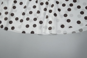 Détail rapproché du tissu léger blanc avec motif de pois noirs et texture plissée