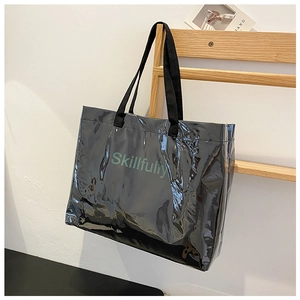 Detail of black glossy tote bag with Skillfully lettering hanging on a wooden rack