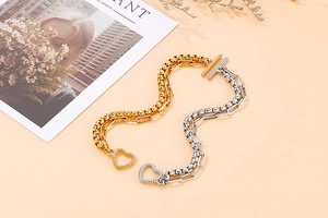 Dettaglio della collana a catena bicolore con pendente a cuore e chiusura a T