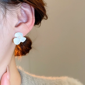 Detail shot of white matte flower petal earrings with center pearl on model ear