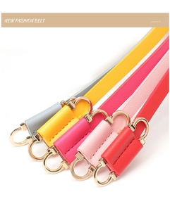 Close-up of vibrant leather skinny belts in five colors with golden D-ring buckles