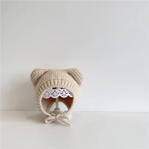 Detail of beige knit baby winter hat featuring cute bear ears and secure chin straps