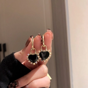Detail of gold-plated heart earrings featuring black enamel and sparkling crystals