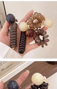 Detailed macro view of spiral phone line hair ties with colorful beads in brown and beige