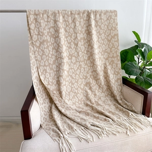 Detail of soft leopard print jacquard scarf with decorative tassels on an armchair
