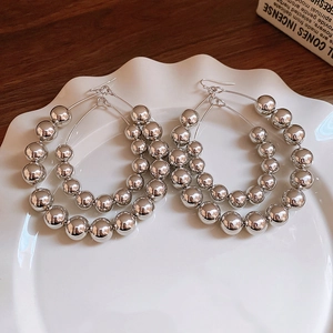 Détail de boucles d'oreilles créoles à billes argentées brillantes sur un plat en céramique