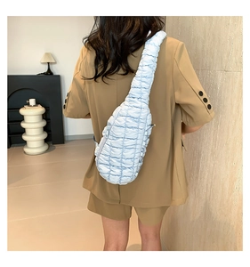 Gros plan d'un sac nuage matelassé bleu clair avec bandoulière plissée sur un mannequin