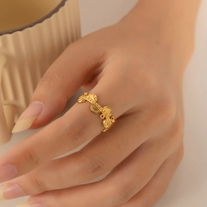 Close-up of golden hollow geometric ring with rhythmic texture on model's finger