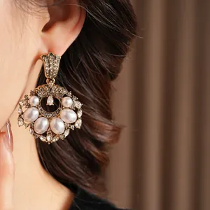 Vintage gold pearl drop earrings with sparkling rhinestones on model side profile