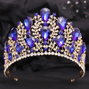 Detail of baroque gold crown featuring large blue gemstones and sparkling crystals on black