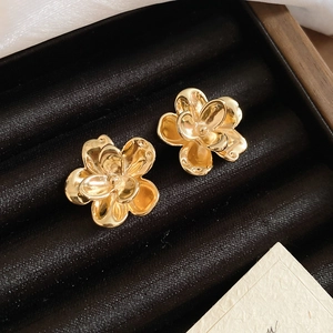 Macro shot of gold flower stud earrings resting on black velvet jewelry padding