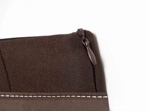 Détail de couture sur tissu marron et cuir avec une fermeture éclair métallique de qualité