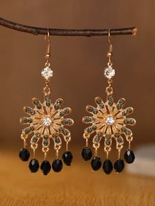 Detail of golden bohemian sun flower earrings with rhinestones and black beaded tassels