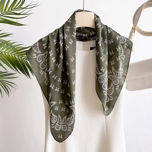 Olive green paisley silk-like square scarf styled on white dress with lifestyle decor