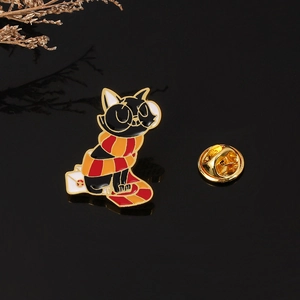 Detailed view of a black enamel cat brooch with a red scarf and a metal butterfly clasp