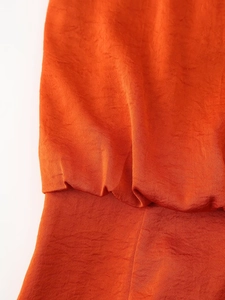 Macro detail of orange satin fabric showing rich woven texture and subtle glossy sheen