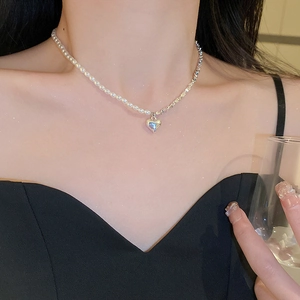 Détail macro du collier asymétrique en perles et chaîne argentée avec pendentif cœur