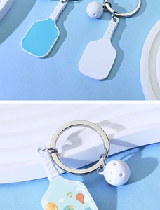 Macro detail of pickleball paddle keychains with miniature balls in blue and white