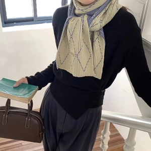 Detail of soft knit scarf with beige and purple diamond pattern on a female model