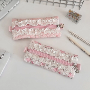 Quilted pink cotton pencil case with lace trim and floral zipper pull on desk