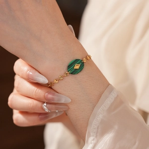 Détail d'un bracelet vintage en chaîne dorée avec pierre malachite verte et soleil