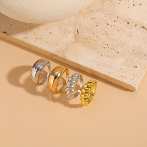 Polished and twisted 14K gold and silver plated rings on a neutral textured stone