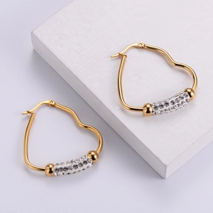 Elegant gold heart earrings with sparkling rhinestones on a minimalist white display