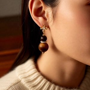 Detail of vintage tiger eye gourd earrings with cross studs and zircon accents on a model