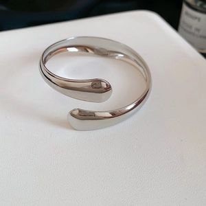 Detailed view of silver polished crossover cuff with teardrop ends and sleek metallic finish