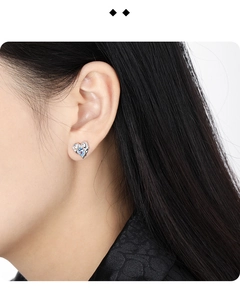 Close-up of S925 silver heart earring with blue gemstone worn on model's ear
